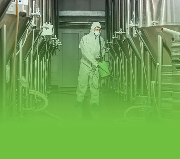 Reinigungskraft mit Schutzkleidung bei der Reinigung einer Industrieanlage